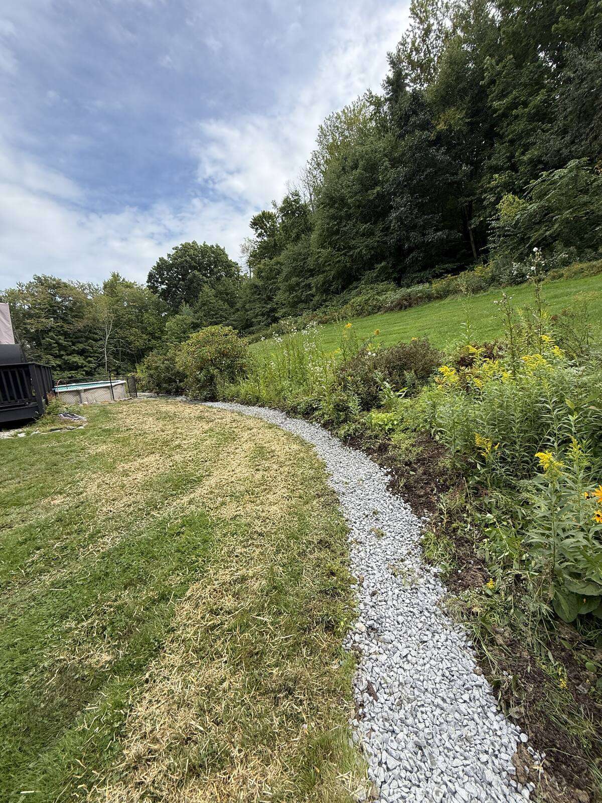Finished french drain curving along the planting bed in East Chatham, NY
